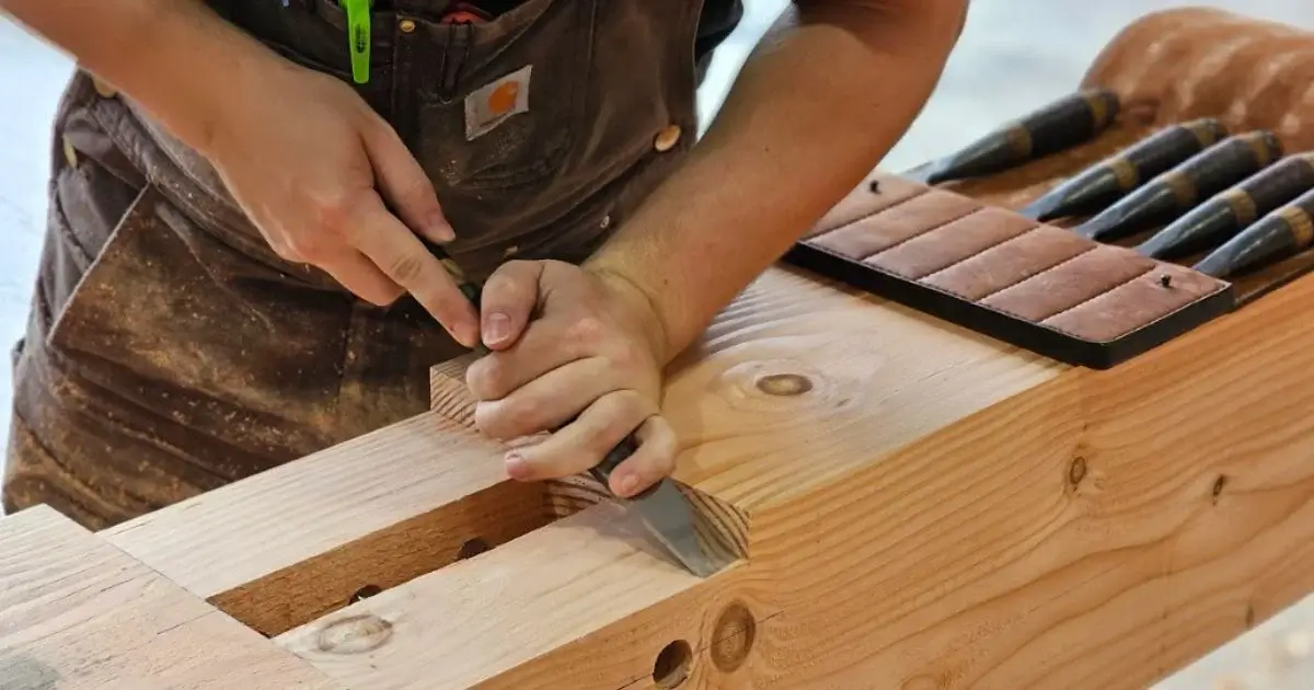 Woodworker chiseling timber joint for custom timber frame construction