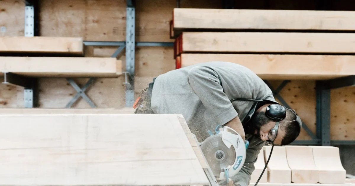 Worker cutting large timber beam with circular saw